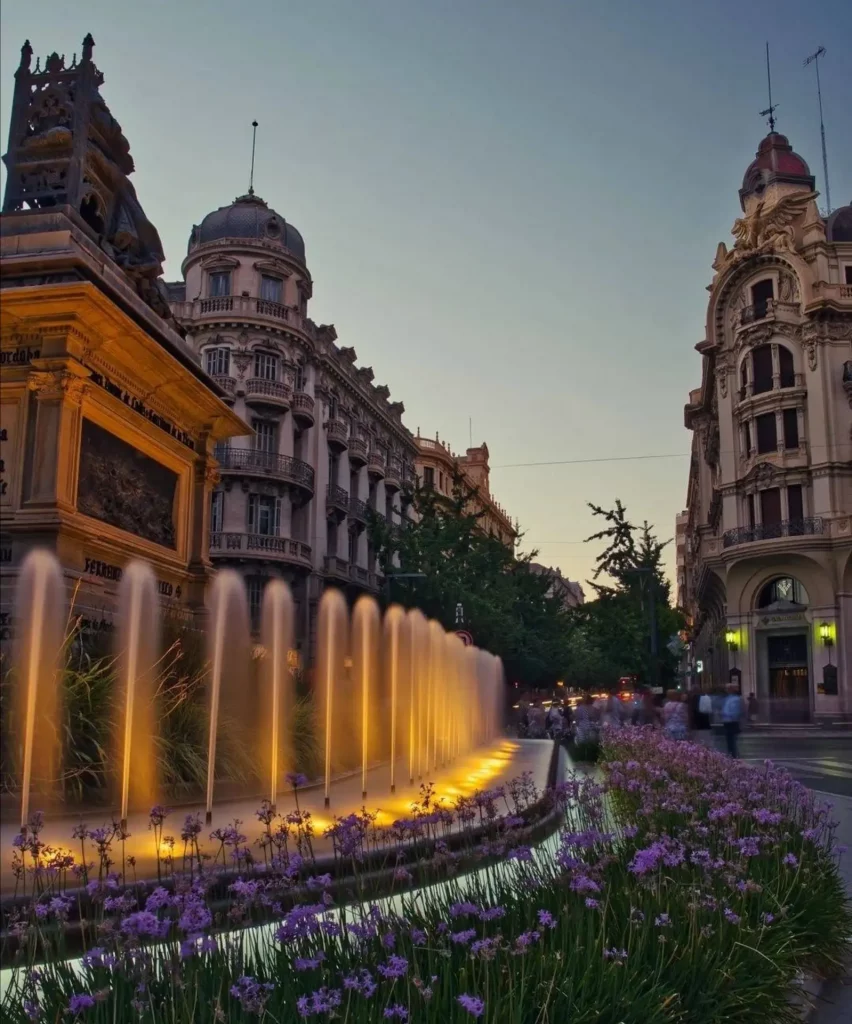 Centro histórico iluminado, incluyendo plazas con fuentes como esta cerca de la Avenida de la Constitución.