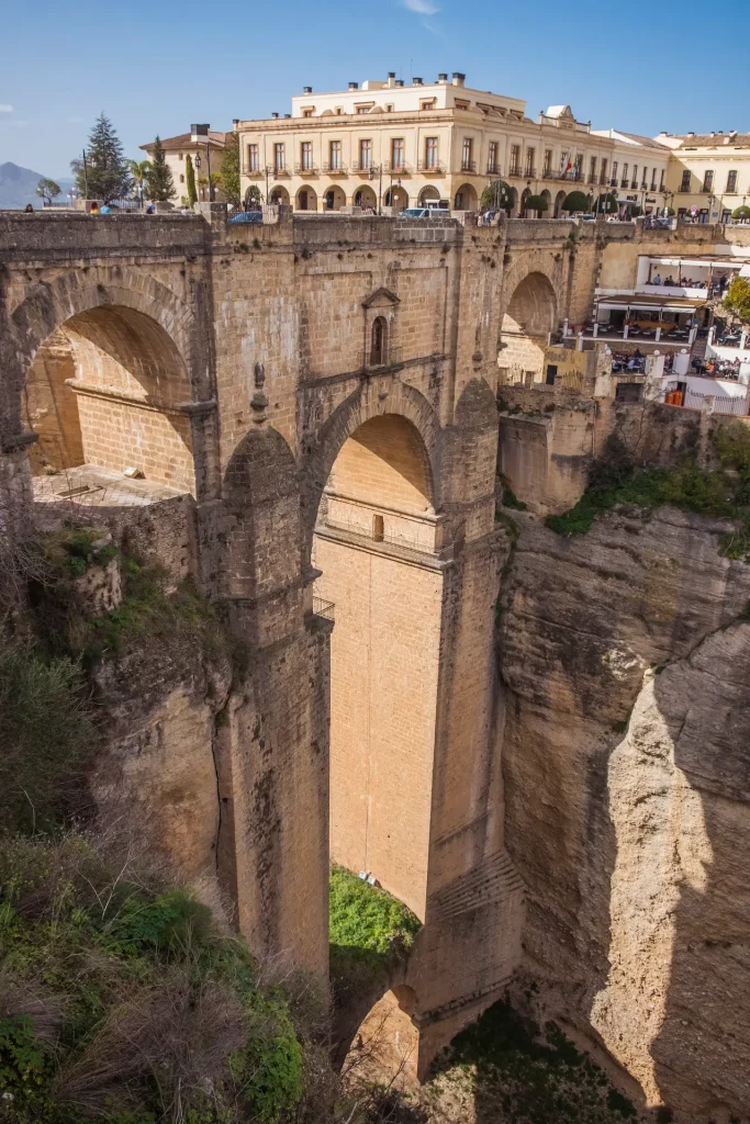 Excursión privada a Ronda desde Sevilla: vista panorámica del famoso Puente Nuevo y el abismo del Tajo en un tour guiado por Andalucía.