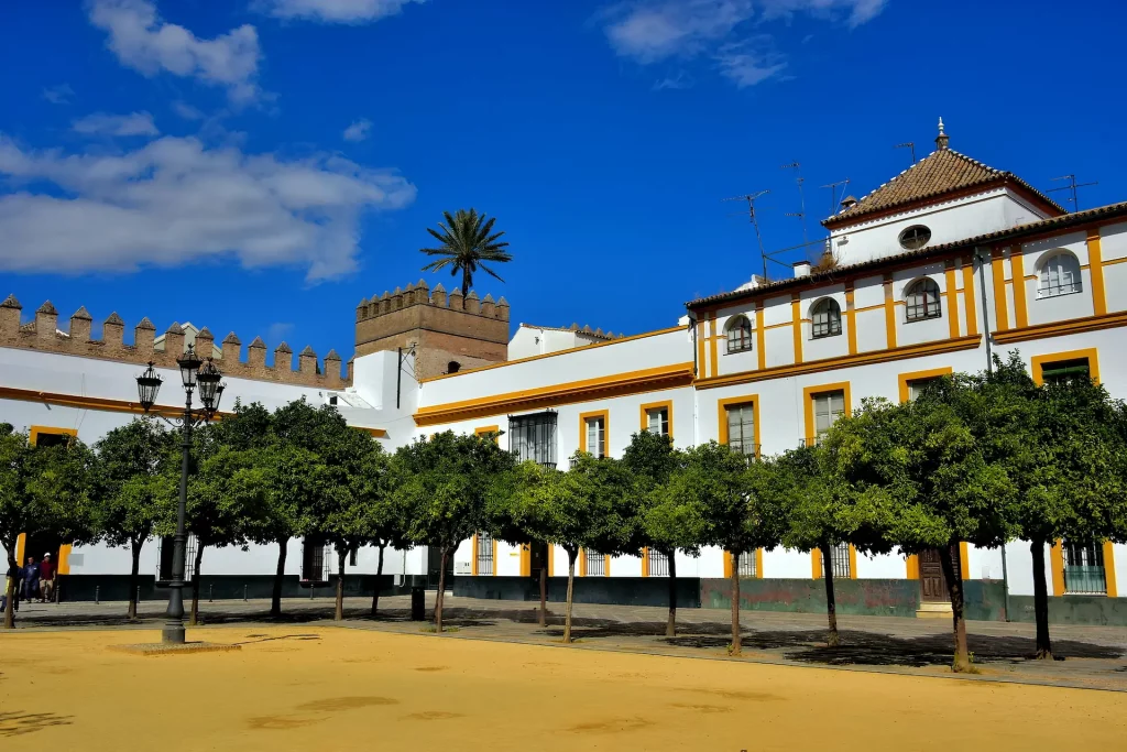 Tour por el Barrio de Santa Cruz en Sevilla: el histórico Patio de Banderas con vistas a la muralla del Alcázar y arquitectura tradicional andaluza.
