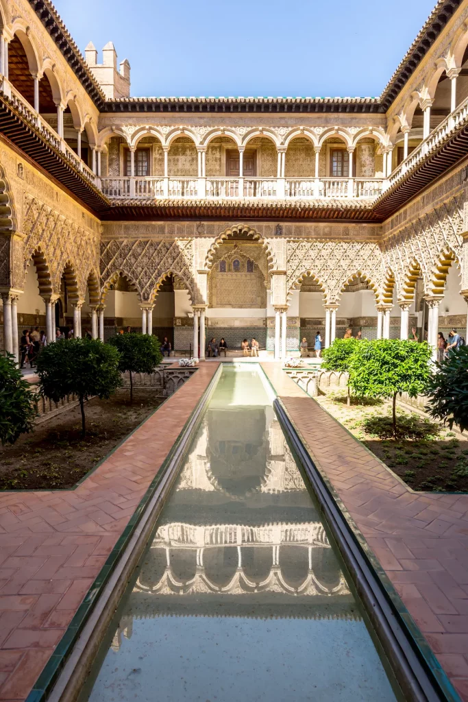 Visita guiada al Real Alcázar de Sevilla: el Patio de las Doncellas con sus icónicos arcos y estanque, un imprescindible de Andalucía.