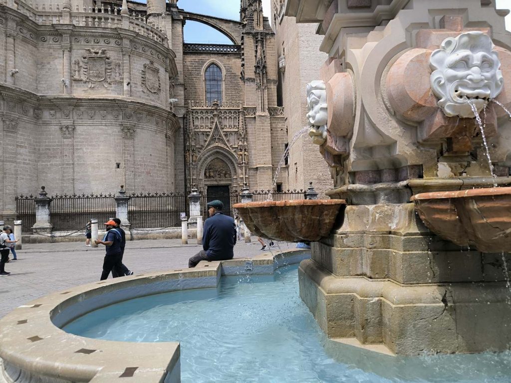 Sevilla patrimonio humanidad destino turístico Fuente ornamental con la fachada de la Catedral de Sevilla al fondo en la Plaza del Triunfo